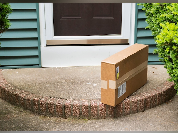 A box left on the steps of a house, possibly awaiting delivery or pickup.